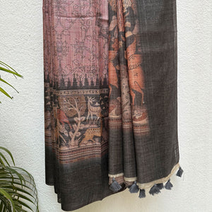Closeup of the forest print border with charcoal solid border and kalamkari jaal pattern body, on a wooden hanger