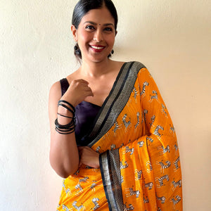 Model wearing Zebra Cadabra orange printed cotton saree with zebra motifs and grey border, styled with minimal jewellery and black blouse, by The Thread Weavers