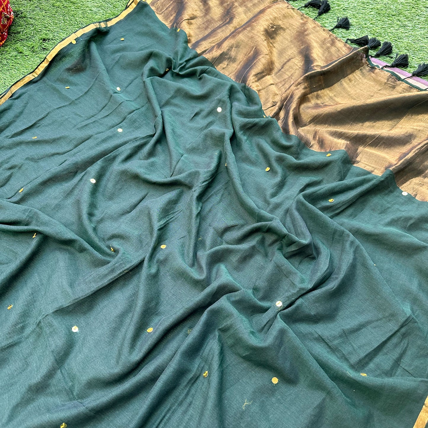 Delicate gold embroidered sequins on a forest green mul cotton saree with handcrafted detailing.