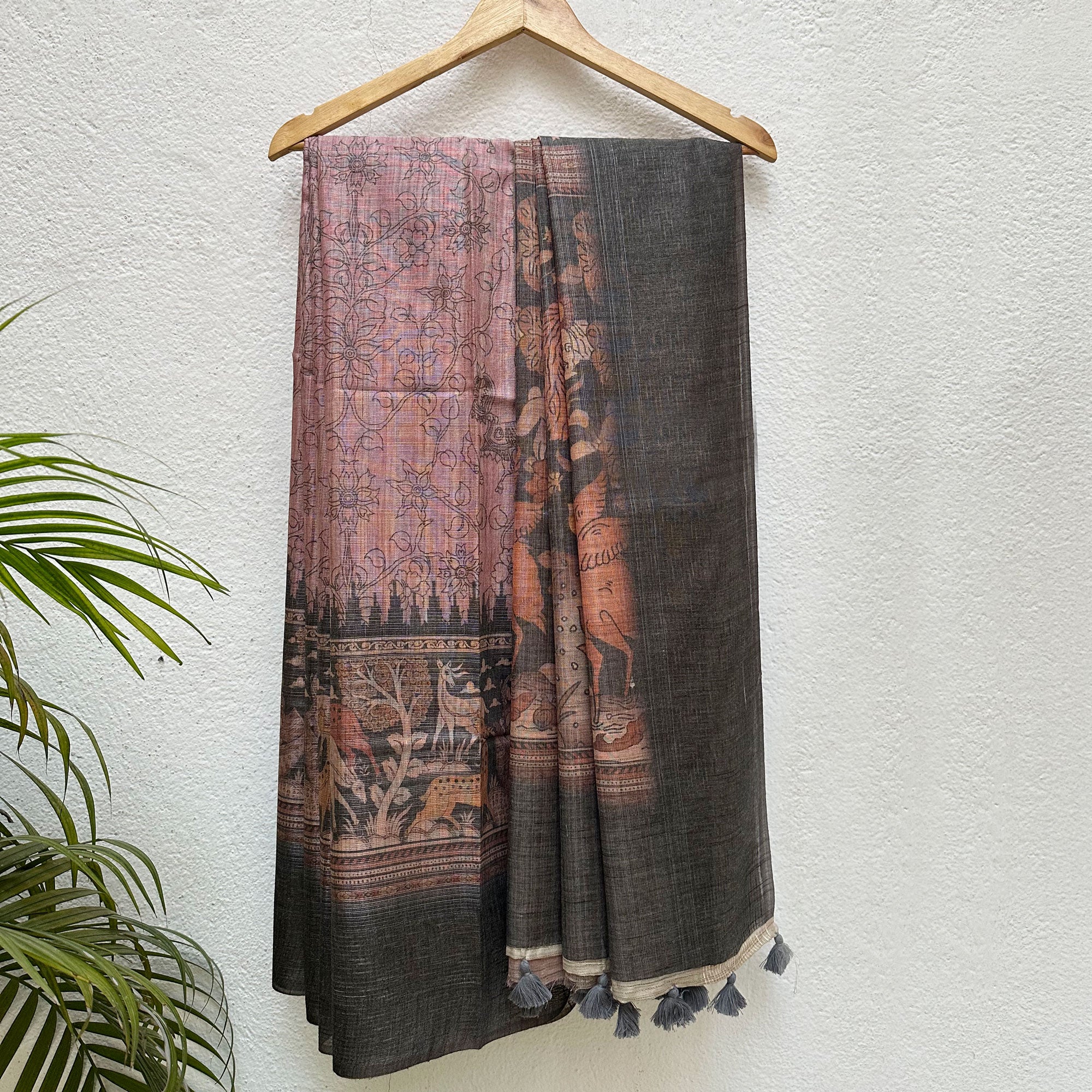 Aranya Printed Tissue Silk Saree in rose and charcoal with a forest print border and kalamkari jaal pattern body, on a wooden hanger
