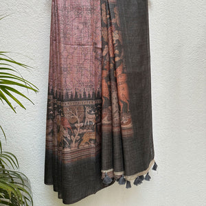 Closeup of the forest print border with charcoal solid border and kalamkari jaal pattern body, on a wooden hanger