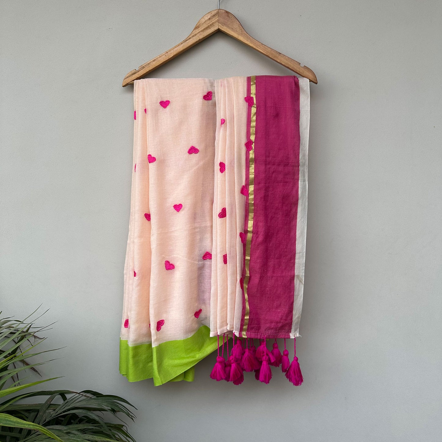 Guava Bloom mul cotton saree in blush pink with embroidered heart motifs, lime green border and handcrafted tassels.