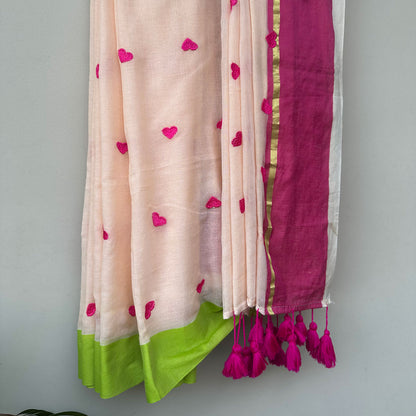Lightweight mul cotton saree in pastel pink with pink embroidered hearts and vibrant lime green edging.