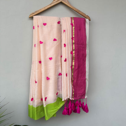 Artistic handcrafted mul saree with heart motifs, colour-blocked pink pallu and statement tassel detailing.