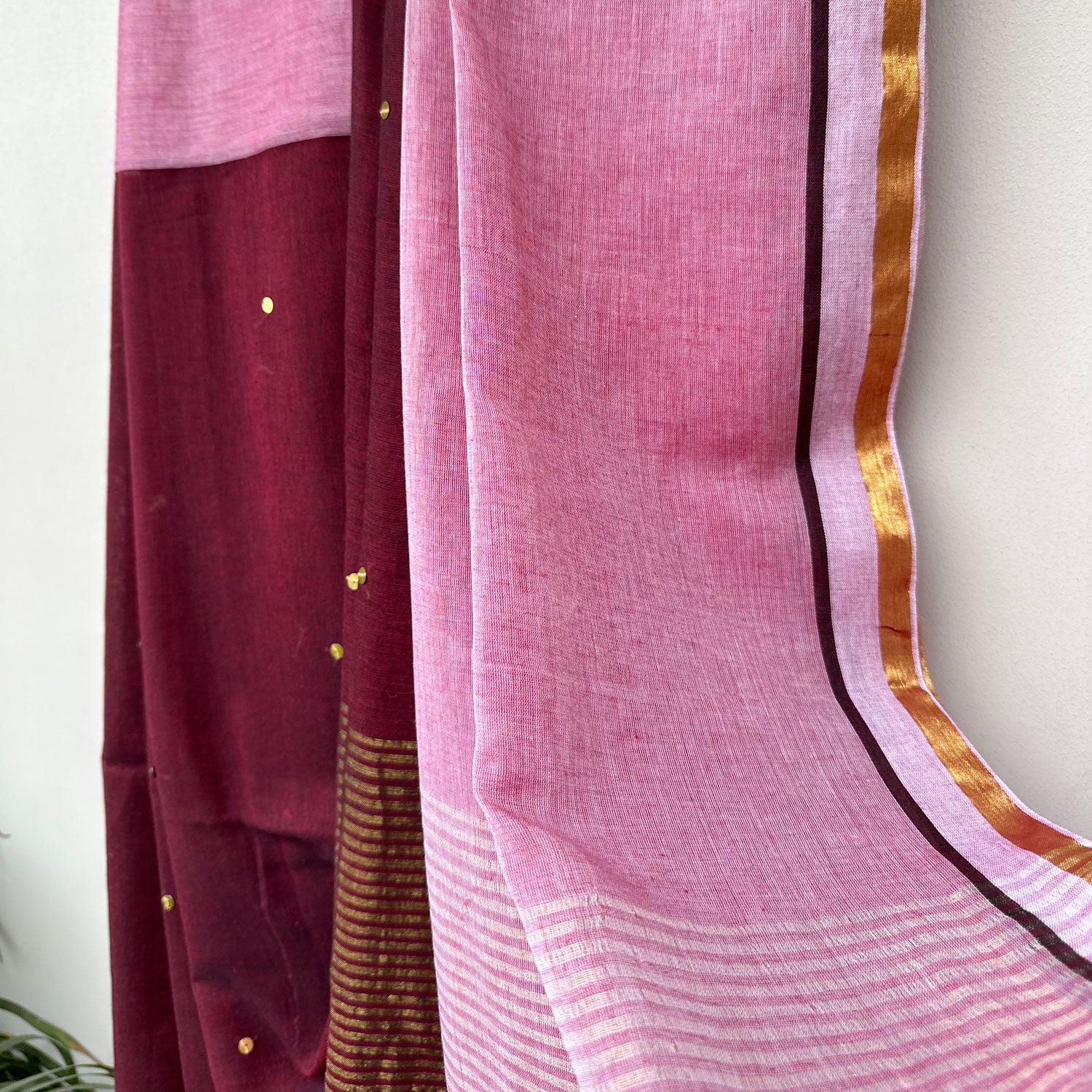 Lightweight embroidered mul saree in wine and pink tones with shimmering sequin accents and striped pallu.