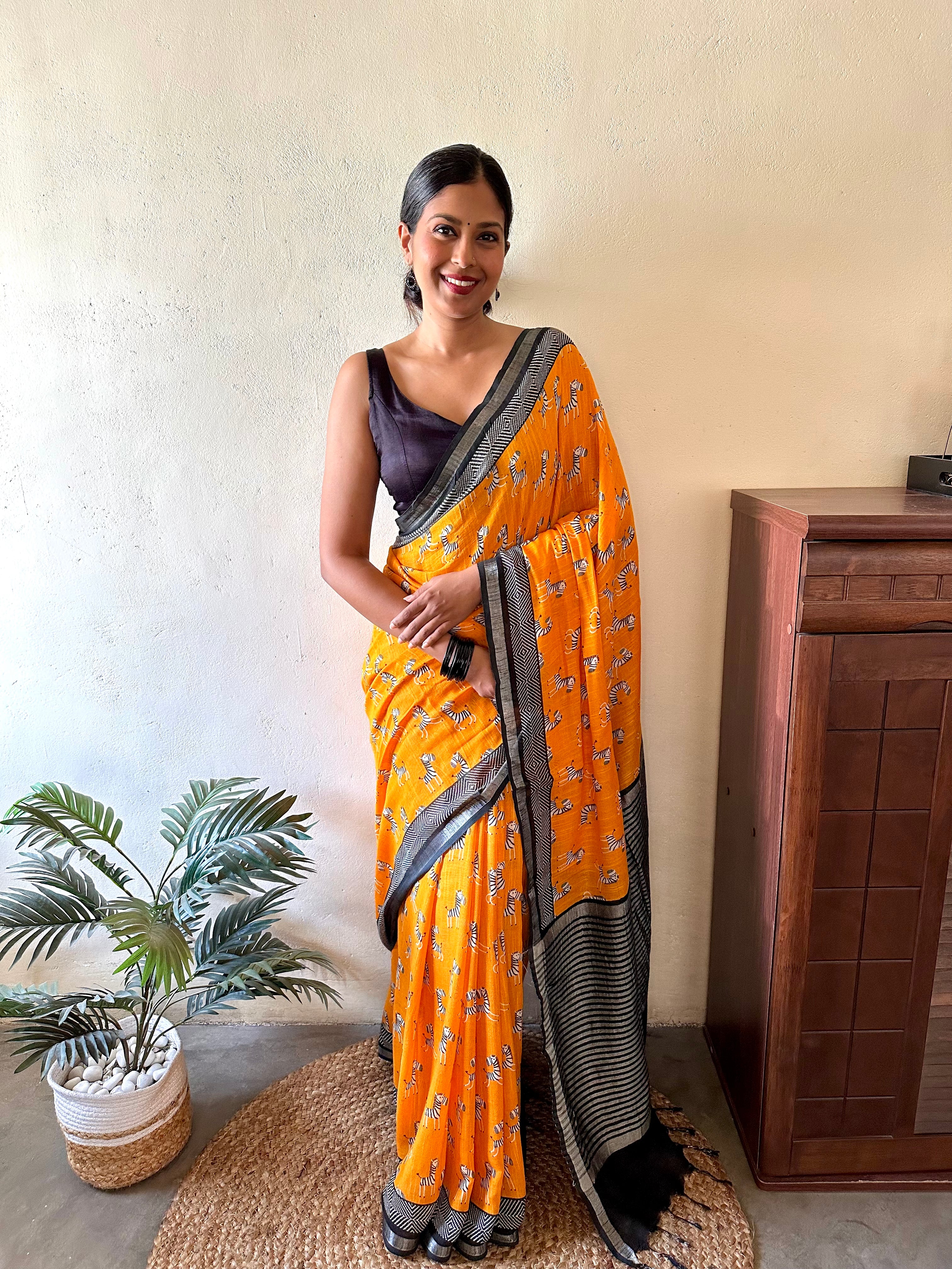 Model wearing Zebra Cadabra orange printed cotton saree with zebra motifs and grey border, styled with minimal jewellery and black blouse, by The Thread Weavers
