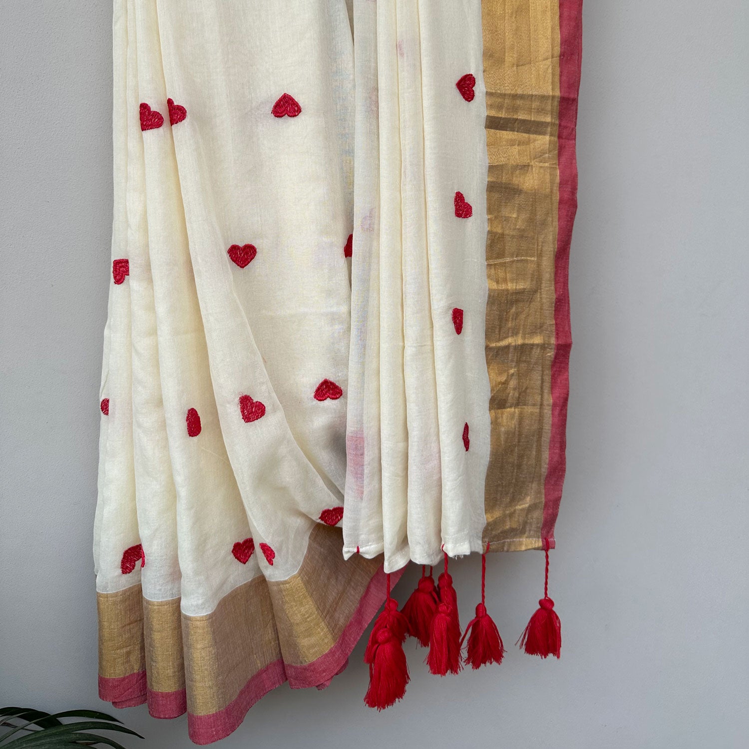Lightweight mul cotton saree in ivory with scattered red heart motifs and elegant gold border accents.