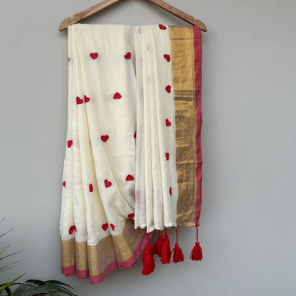 Handcrafted ivory embroidered saree with red heart motifs, contrast red border and contemporary Indian design.