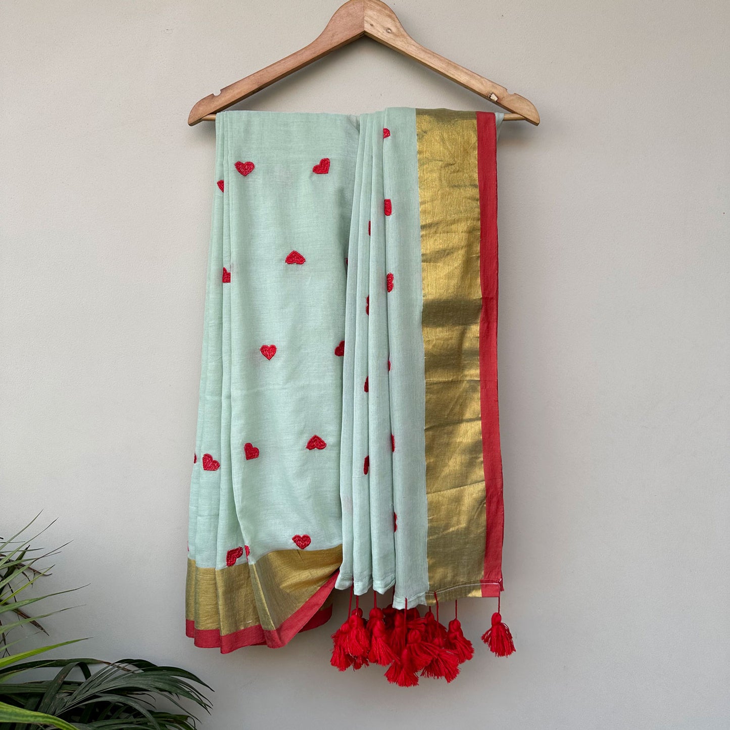 Mint mul cotton saree with embroidered heart motifs, gold border and handcrafted red tassels.
