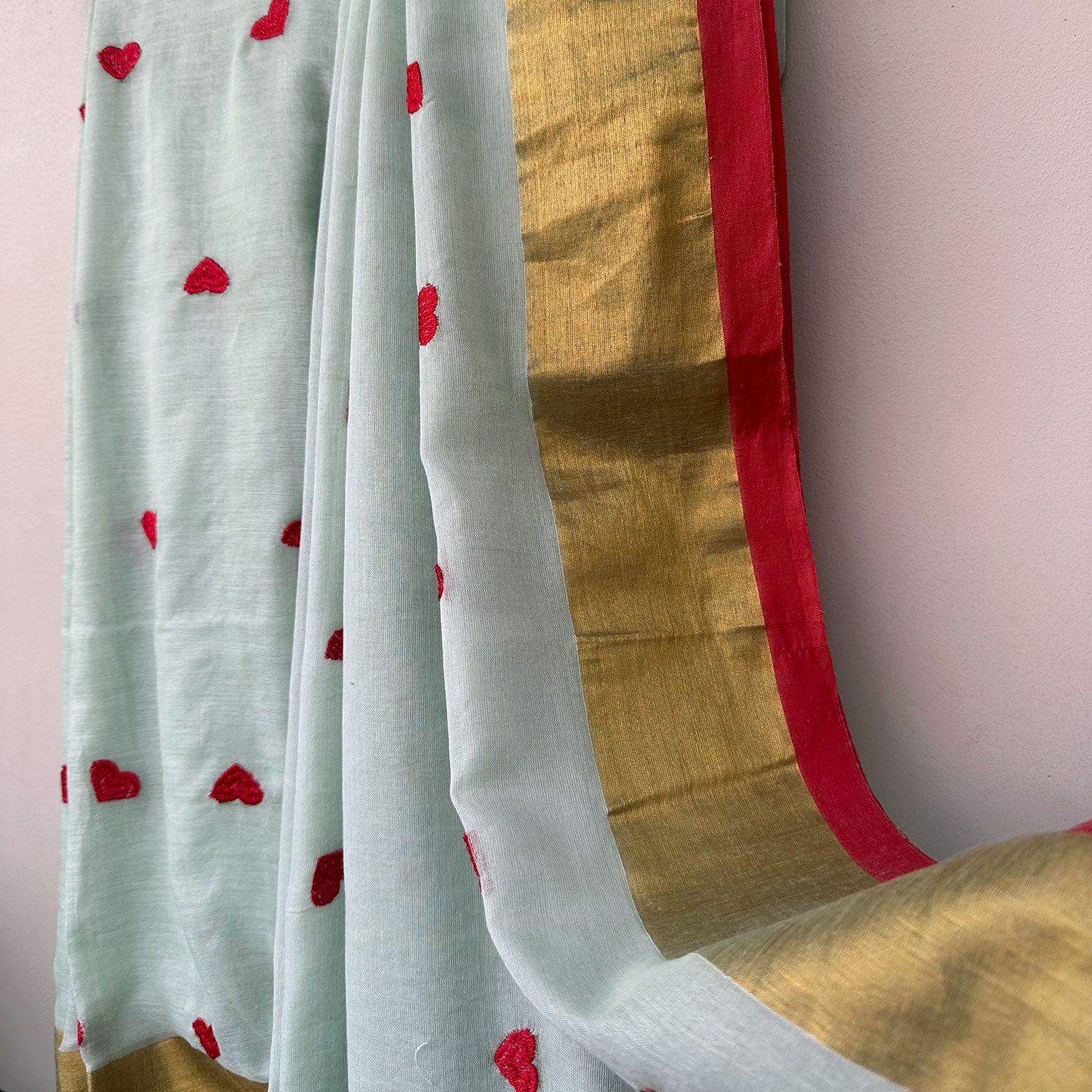 Lightweight mul cotton saree in soft mint with scattered heart motifs and elegant gold border accents.