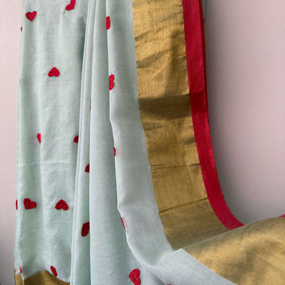 Lightweight mul cotton saree in soft mint with scattered heart motifs and elegant gold border accents.