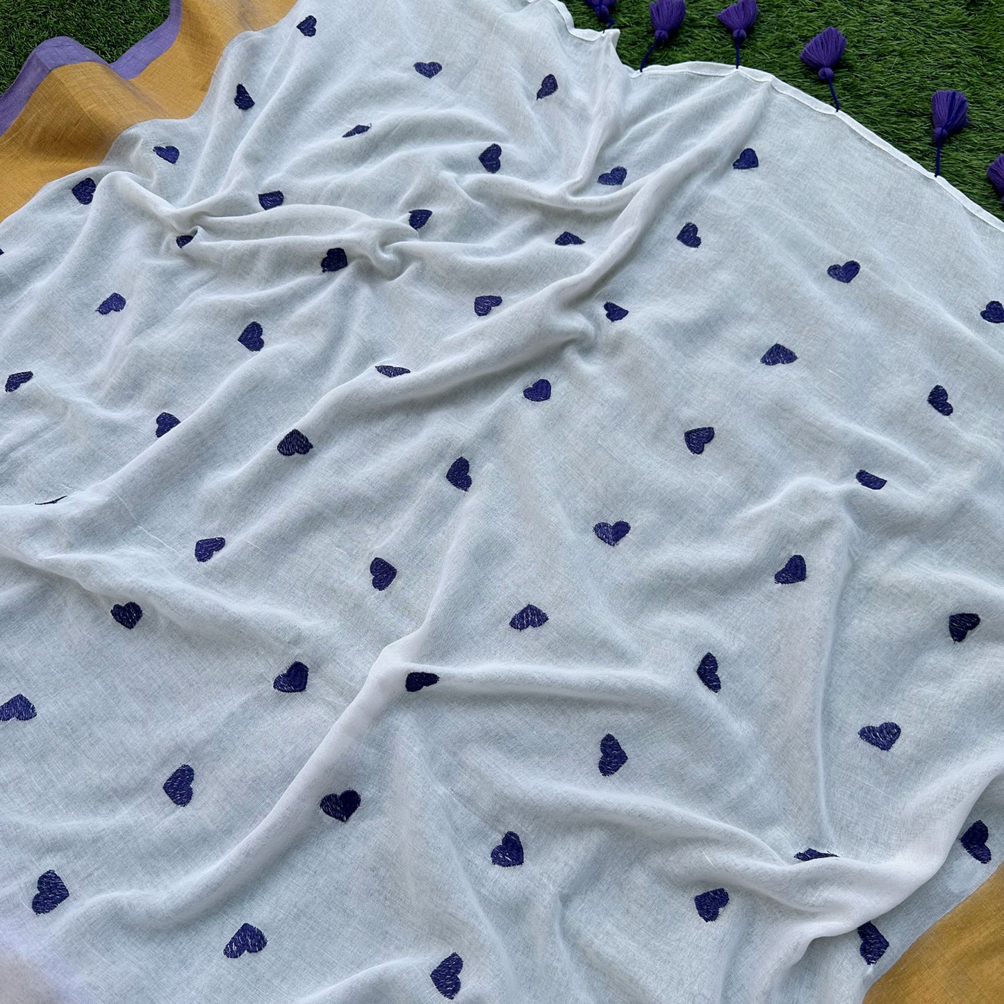 Delicate lavender heart embroidery on a white mul cotton saree with subtle gold border accents.