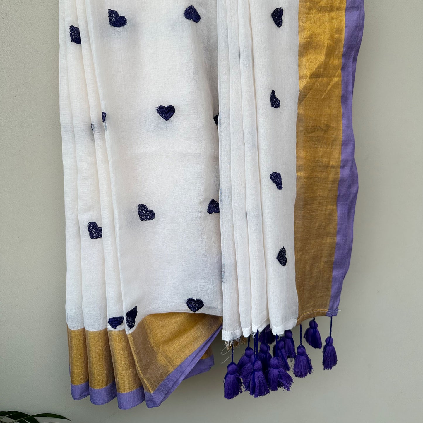 Contemporary white mul saree featuring delicate heart embroidery, lavender accents and lightweight drape.