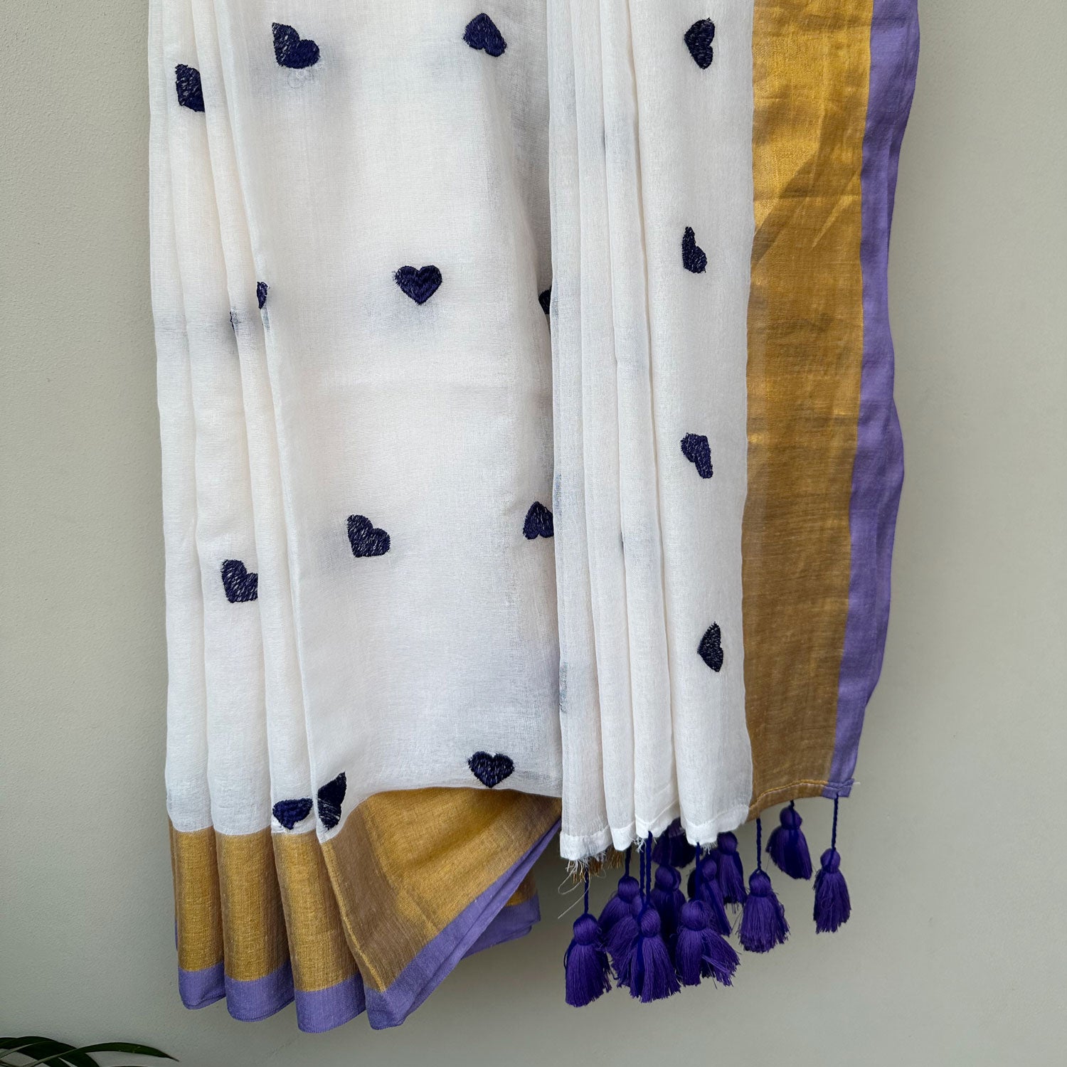Contemporary white mul saree featuring delicate heart embroidery, lavender accents and lightweight drape.