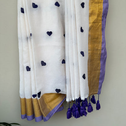 Contemporary white mul saree featuring delicate heart embroidery, lavender accents and lightweight drape.