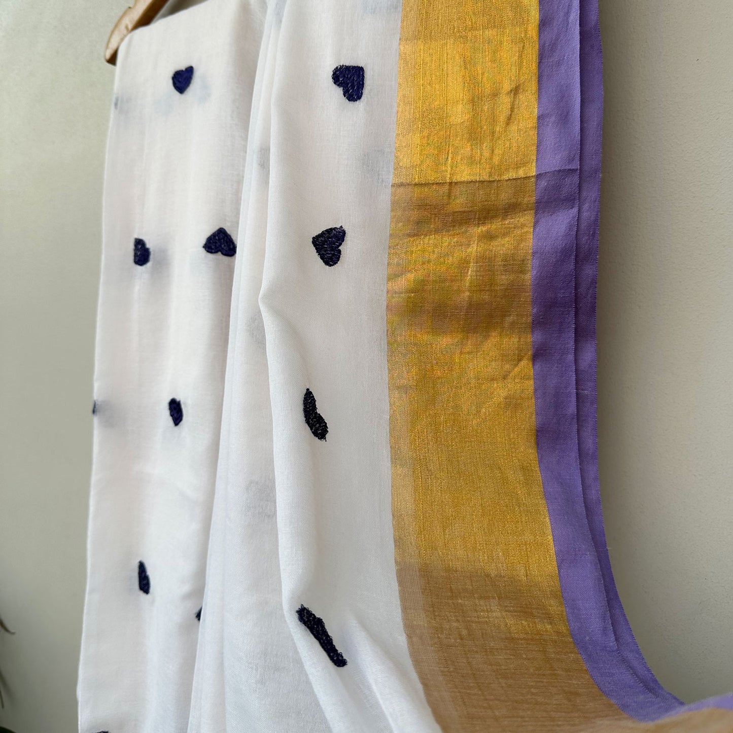 Soft white mul cotton saree with scattered lavender heart motifs and elegant gold border detailing.