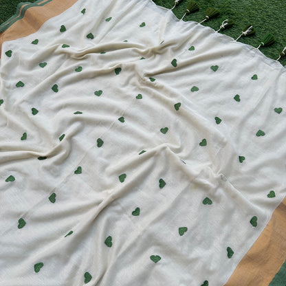 Delicate green heart embroidery on an ivory mul cotton saree with subtle gold border accents.