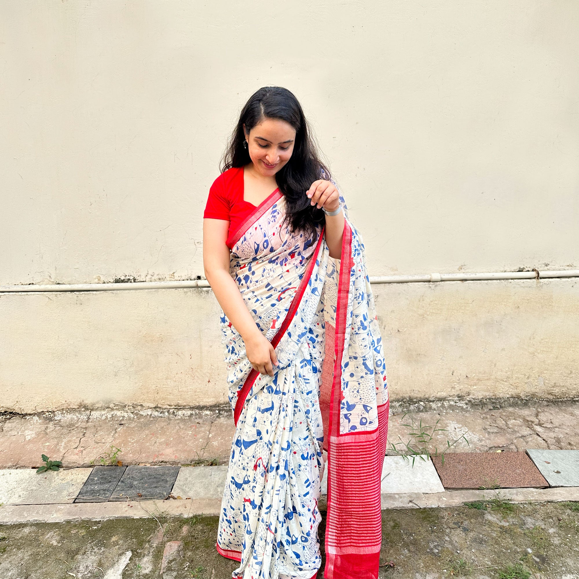 Founder wearing Purr-suasion ivory cotton saree with blue illustrated cat crowd print and bold red zari pallu paired with red blouse, Zoomies Collection by Thread Weavers