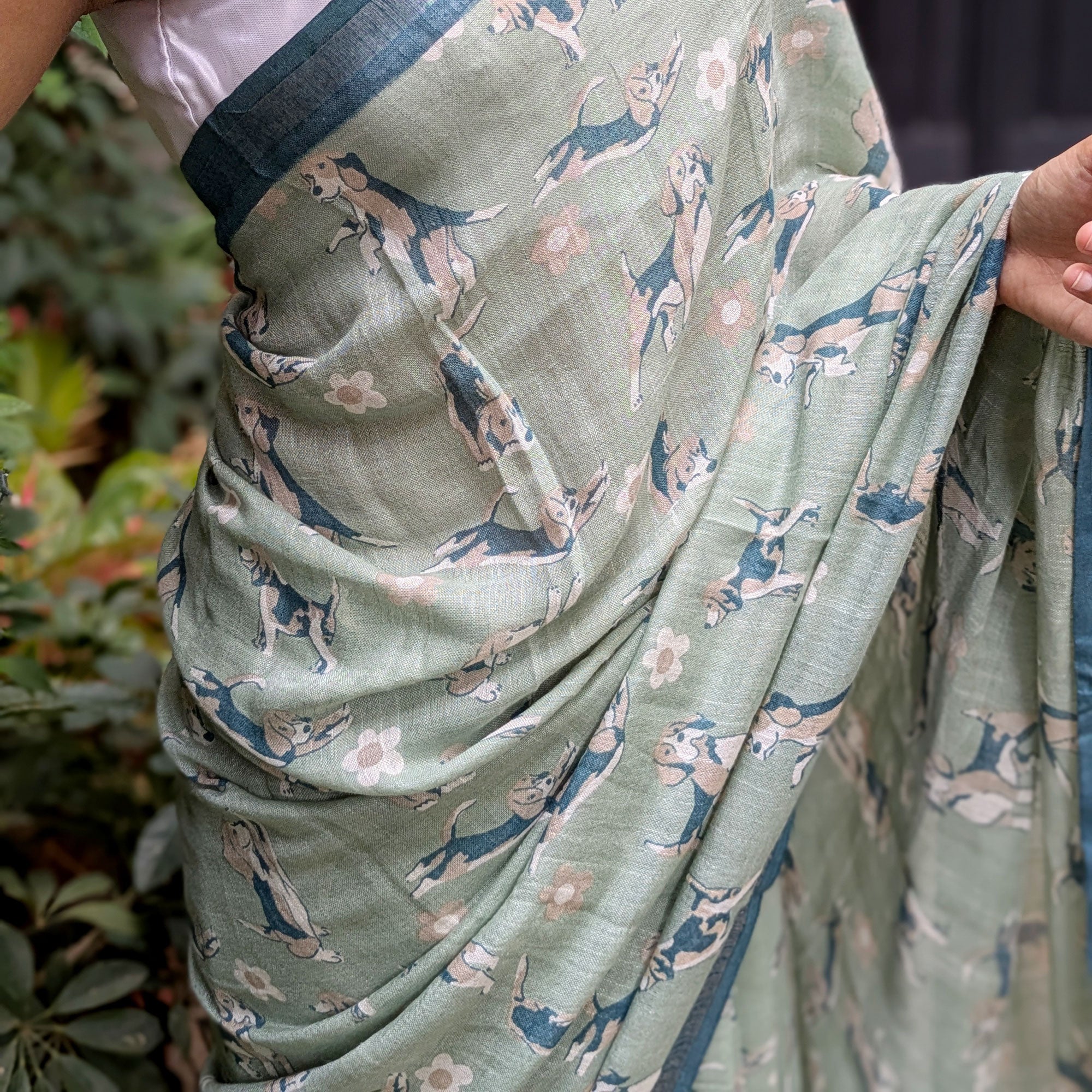 Model wearing The Biscuit Hour sage green cotton beagle print saree with daisy florals and dark teal zari pallu, Zoomies Collection Thread Weavers