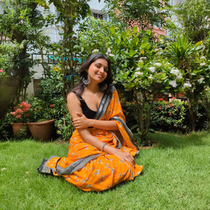 Model wearing Zebra Cadabra orange printed cotton saree with zebra motifs and grey border, styled with minimal jewellery and black blouse, by The Thread Weavers