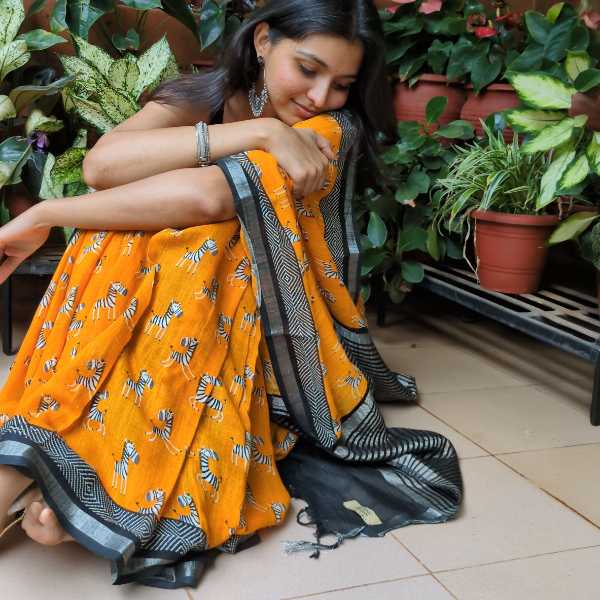 Model wearing Zebra Cadabra orange printed cotton saree with zebra motifs and grey border, styled with minimal jewellery and black blouse, by The Thread Weavers