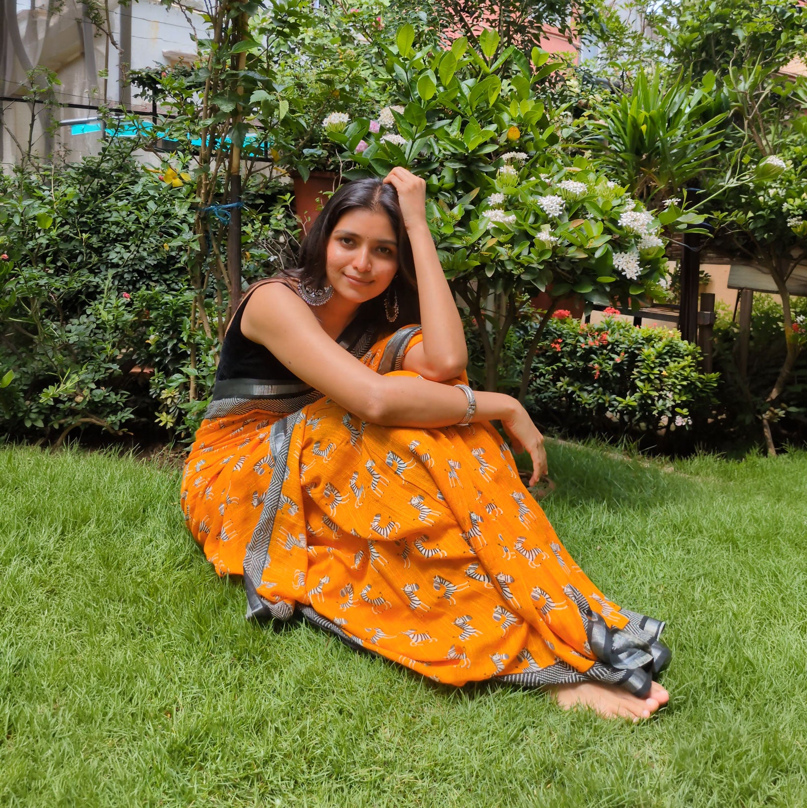 Model wearing Zebra Cadabra orange printed cotton saree with zebra motifs and grey border, styled with minimal jewellery and black blouse, by The Thread Weavers